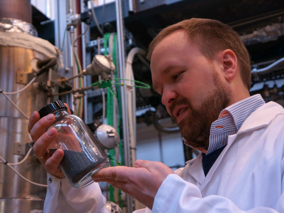 Researcher and section head Werner Filtvedt with a glass of silicon granules from the fluidized bed, seen in the background. (Photo: Arnfinn Christensen, forskning.no.)