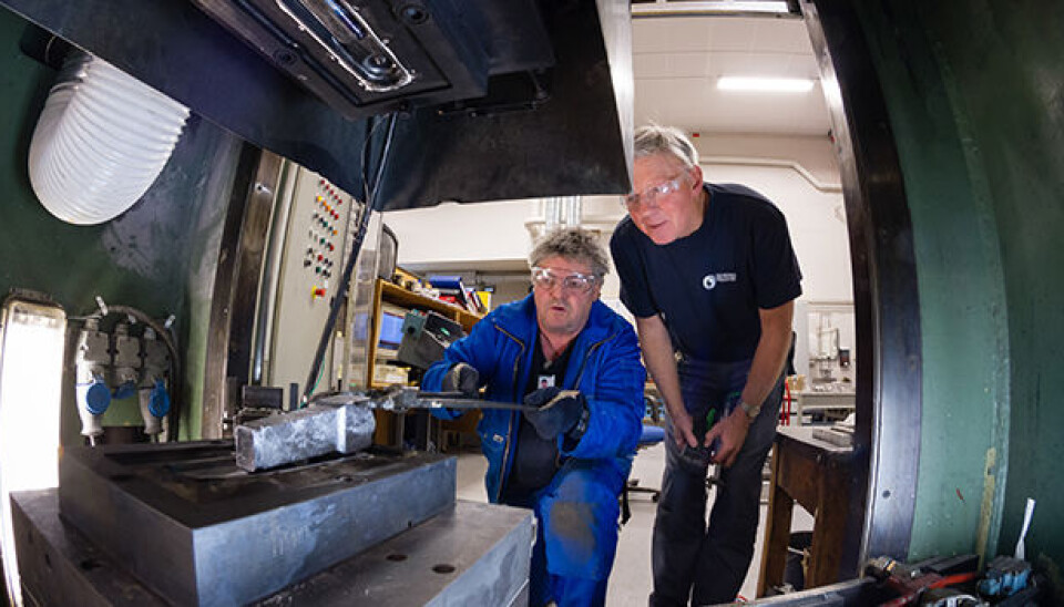 They hope to contribute to energy-efficient manufacture of aluminium vehicle components. Workshop manager Arne Gellein of SINTEF fits the casting into place in the forging machine, together with senior scientist Martin Lefstad. (Photo: SINTEF/Thor Nielsen)