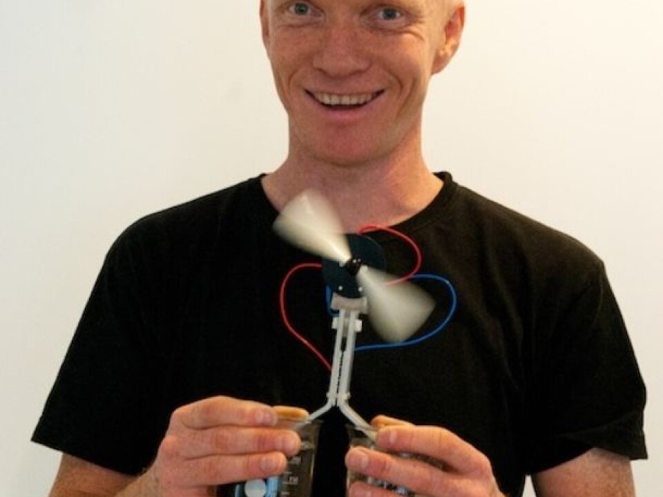 Ole Martin Løvvik demonstrates thermoelectricity with one glass of cold and one glass of hot water. The new technology utilises the temperature difference and generates enough energy to operate a rapidly rotating fan. (Photo: Yngve Vogt/University of Oslo)