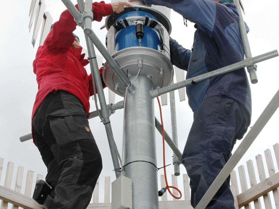 Scientists conduct maintenance work inside one of two wind fences surrounding a precipitation gauge at Haukeliseter. (Photo: Ole Jørgen Østby, Norwegian Meteorological Institute)