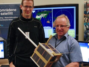 Øystein Helleren (left) and Richard B. Olsen show off a full-scale model of the AISSat-1 in the control room of the Norwegian Defence Research Establishment, where signals from the satellite are monitored. The satellite is a cube, 20x20x20 cm, and the silver pole sticking out is the antenna that catches signals from ships. (Photo: Arnfinn Christensen, forskning.no) Øystein Helleren (left) and Richard B. Olsen show off a full-scale model of the AISSat-1 in the control room of the Norwegian Defence Research Establishment, where signals from the satellite are monitored. The satellite is a cube, 20x20x20 cm, and the silver pole sticking out is the antenna that catches signals from ships. (Photo: Arnfinn Christensen, forskning.no)