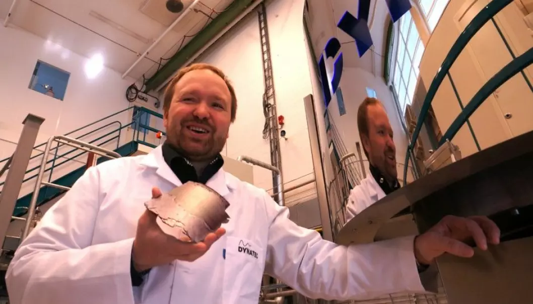The new version of the Danatec company’s centrifuge can produce pure silicon without cooling the hardware. It thus produces silicon 40 times faster than in traditional production machinery. Research manager Werner Filtvedt at Dynatec shows off a piece of silicon retrieved from the curved inner wall of the centrifuge behind him. (Photo: Arnfinn Christensen)
