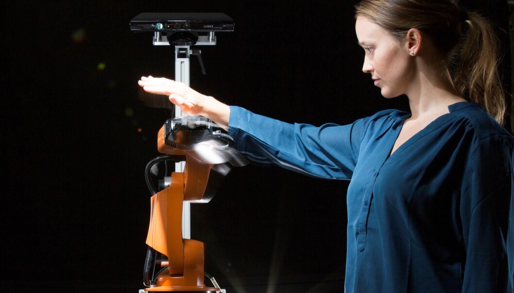 Researcher Marianne Bakken attempting to get close and personal with an orange robot arm – moving in all directions to try to get the robot to collide with her. But it manages to avoid her every time. (Photo: Werner Juvik) Researcher Marianne Bakken attempting to get close and personal with an orange robot arm – moving in all directions to try to get the robot to collide with her. But it manages to avoid her every time. (Photo: Werner Juvik)