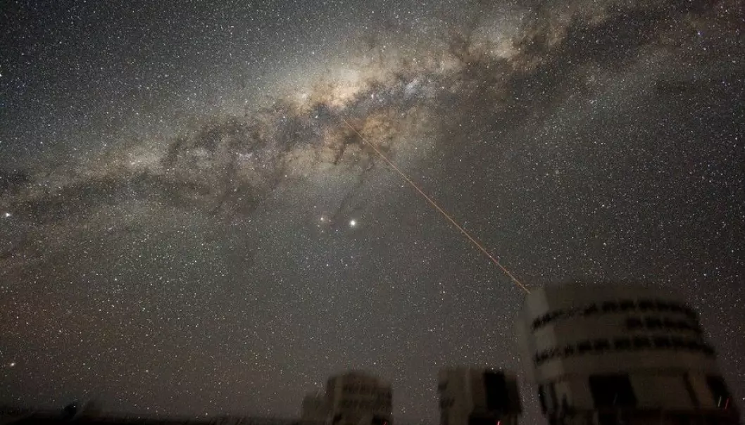 This is the Milky Way in all its glory, as seen from Earth. Could someone be out there trying to contact us? The image shows the ESO VLT telescope. The laser beam in the illustration is from the telescope. (Illustration: Y.Beletsky / ESO / CC BY 3.0)