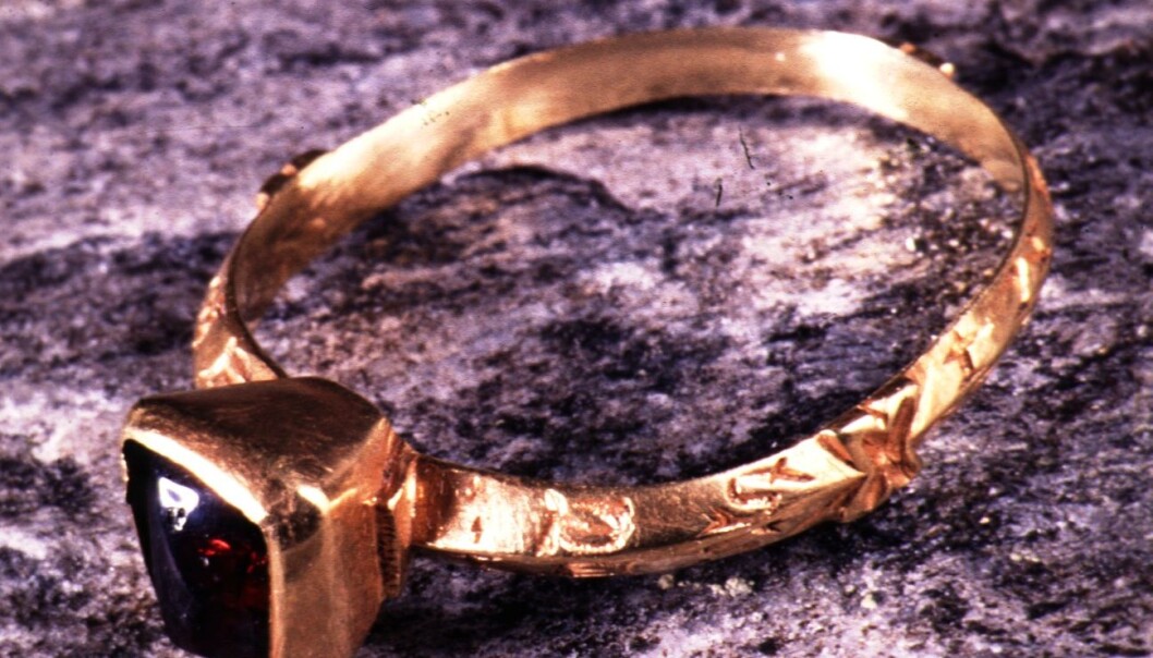 Brit Solli found the gold ring from 1200 AD in a churchyard wall in a small island on the Norwegian west coast. It has a French love inscription along its outer rim. The ring has a red garnet stone. (Photo: Ove Holst at the Collection of National Antiquities/ Museum of Cultural History in Oslo) Brit Solli found the gold ring from 1200 AD in a churchyard wall in a small island on the Norwegian west coast. It has a French love inscription along its outer rim. The ring has a red garnet stone. (Photo: Ove Holst at the Collection of National Antiquities/ Museum of Cultural History in Oslo)