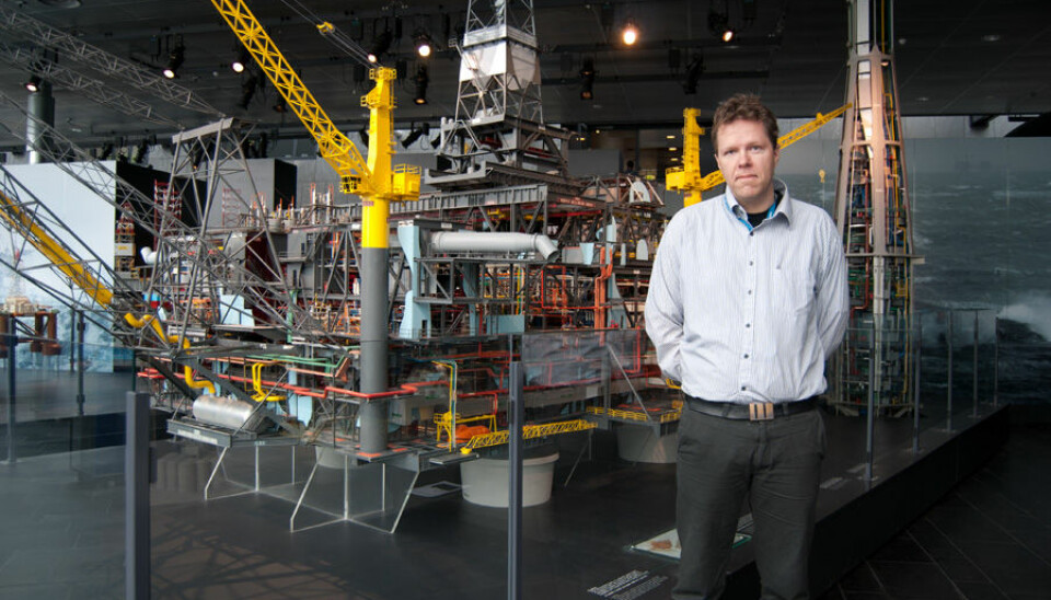 The two-meter tall researcher Gunleiv Hadland at the Norwegian Petroleum Museum in Stavanger poses in front of the Statfjord B model. (Photo: Marianne Nordahl)
