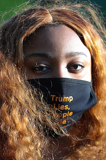 A demonstrator wears a custom face mask reading "Trump Lies, People Die" during a funeral procession demonstration for COVID-19 victims outside of the White House in Washington, U.S., May 20, 2020. Americans of colour, particularly black men, have shared their fears of wearing face masks in public and being mistaken for criminals.