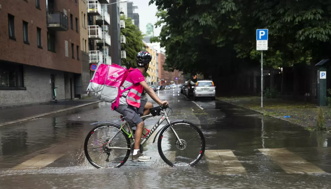 A Norwegian food delivery driver for Foodora working after heavy rainfall.