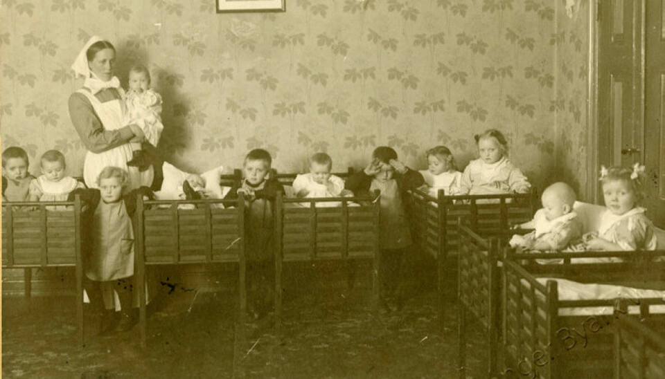 The Cathedral crèche in Stavanger 1919: The picture shows a ward sister and the children in the dormitory. This institution continued to be run by a female deacon or ward sister until 1970.