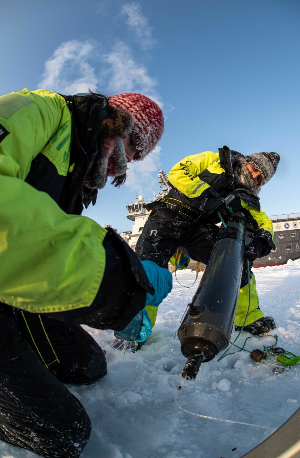 Cheshtaa (to the right) working on the sea ice, retrieving a water sampling bottle from an ice hole