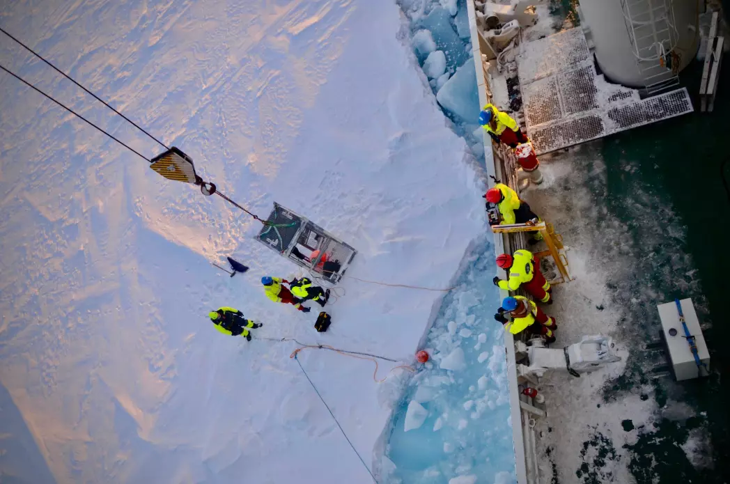 Attaching the sediment traps to an ice floe: Martí, Yasemin and Jørn as a polar bear guard are lifted onto the ice to secure the traps.