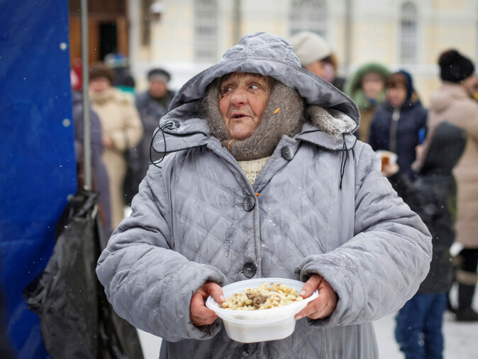 A woman holds out the free meal she has been given by an organization that helps homeless Russians in the city of Stavropol. A woman holds out the free meal she has been given by an organization that helps homeless Russians in the city of Stavropol.