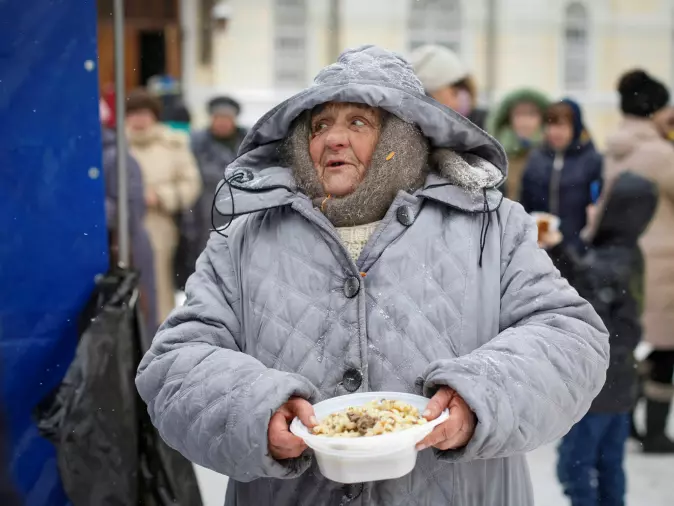 A woman holds out the free meal she has been given by an organization that helps homeless Russians in the city of Stavropol.