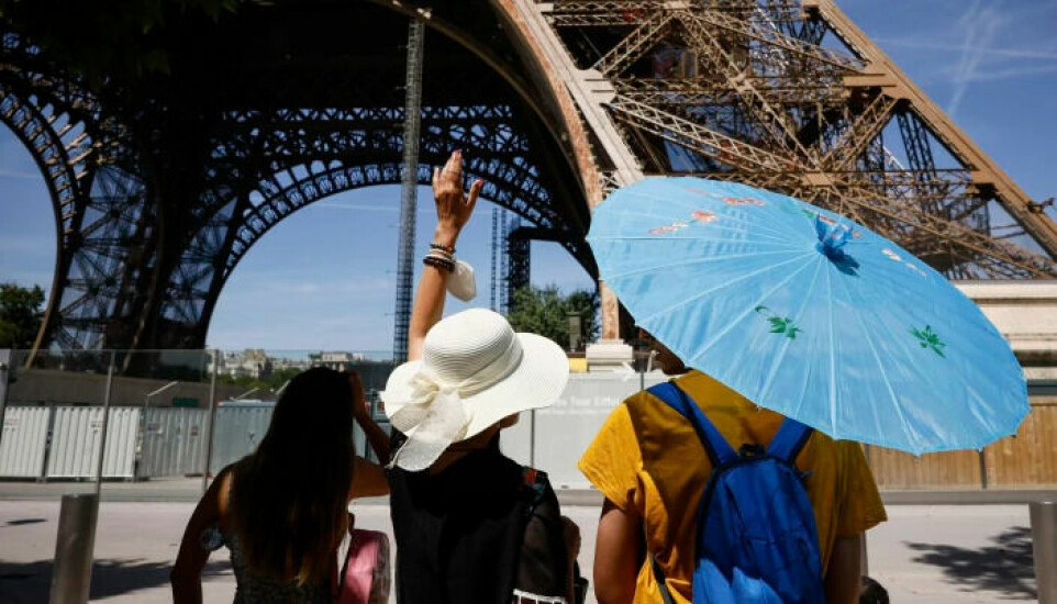 Tourists use parasols and hats to protect themselves from the sun in Paris on a day the temperature was measured at 35°C.