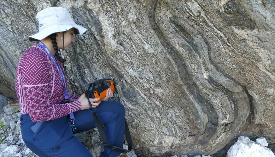 UiO master student Patricia Caixeta Borges measuring the radioactivity of pegmatite wall rock with a scintillometer at Ågskardet, Meløy.