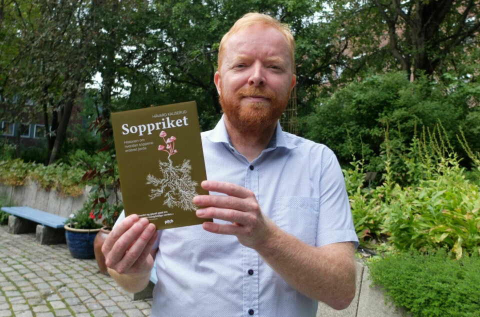 Håvard Kauserud holding up the book he authored.