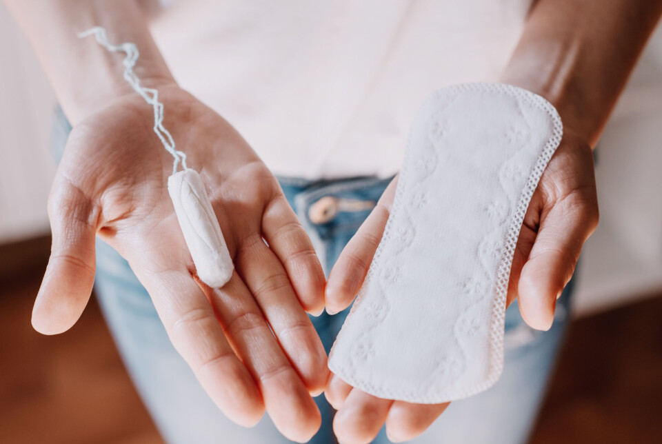Today, menstrual products are a billion-dollar industry. Hender som holder en tampong og et bind.