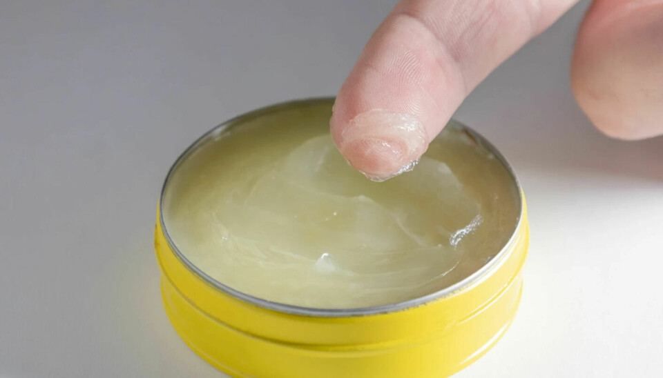 A finger scooping Vaseline out of a container.