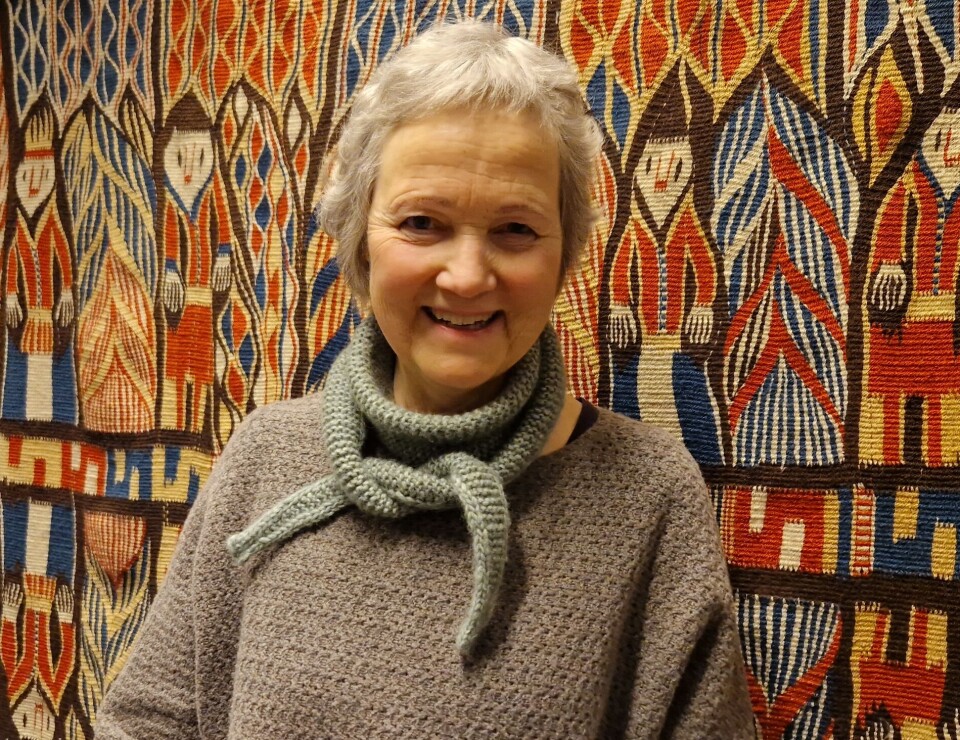 Randi Veiteberg Kvellestad in front of a woven tapestry. She personally uses embroidery as a form of artistic expression.