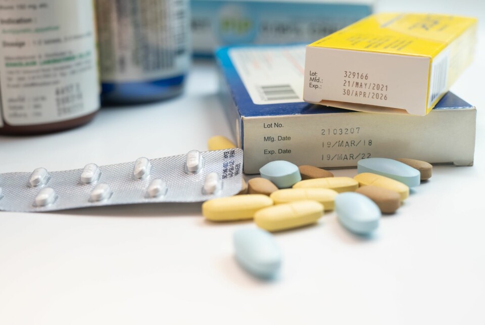 Piller, pillebrett og esker med medisin ligger på et bord med medisinflasker i bakgrunnen. En av eskene har utgått dato.