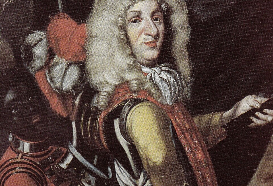 Christian Hansen Ernst (left) is depicted in a painting that hangs in the Eidsvoll Manor House, where Norway’s constitution was drawn up and signed. He was enslaved by Count Ulrik Frederik Gyldenløve (right). Ernst may have been born in England and bought by Gyldenløve as a small boy. Ernst became free and got a job in the postal service. His further fate is uncertain, but he may have been postmaster in Kragerø and might have been killed in a murder of jealousy, according to the Norwegian history site norgeshistorie.no. Christian Hansen Ernst er avbildet på et maleri som henger i Eidsvollsbygningen. Han var gjort til slave av grev Ulrik Frederik Gyldenløve
