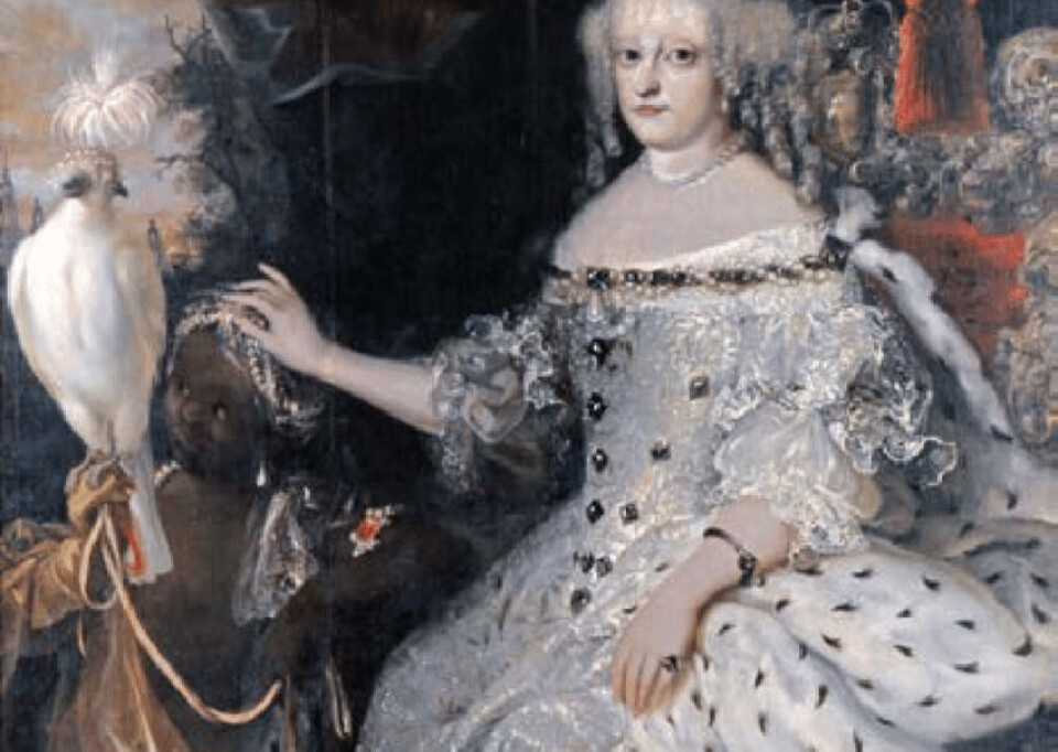 Portrait of Queen Sophie Amalie of Denmark-Norway. A young boy in a turban is part of the painting. This is typical of how slaves were depicted, according to Hanne Østhus. They were included as an exotic element and status symbol. Portrett av dronning Sophie Amalie av Danmark-Norge. En ung gutt i turban er med på maleriet.