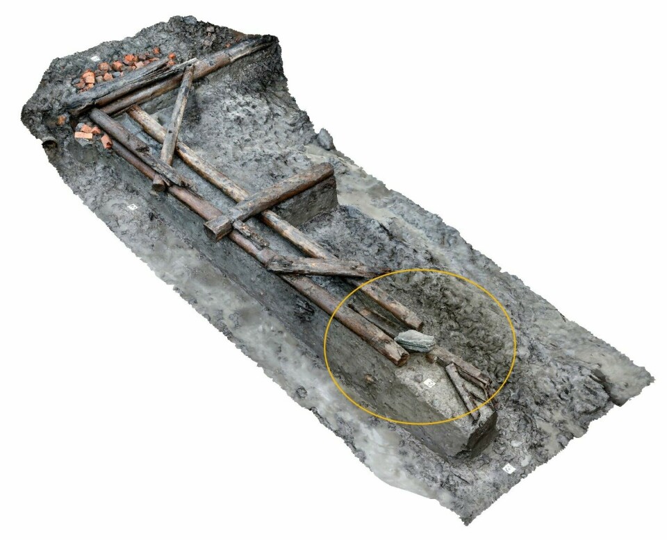Under this foundation of a 14th-century wharf, archaeologists found the ship part. You can see the part circled just below the stone to the right in the picture.