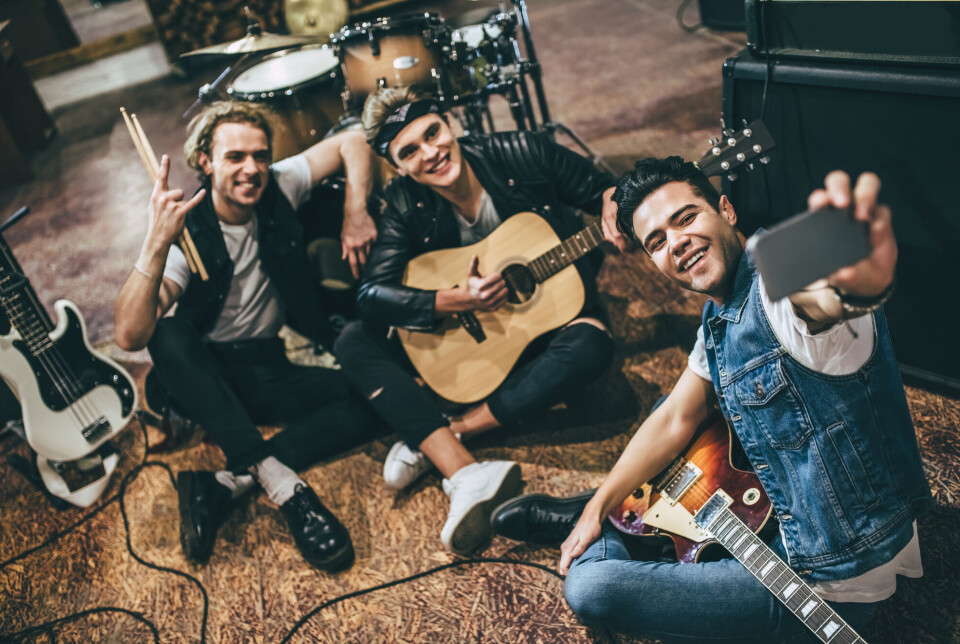 Eirik Jacobsen's research shows that musicians feel pressure to frequently share content with their followers. Three men with instruments taking a selfie.