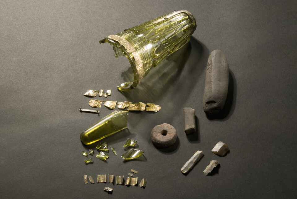 Archaeologist Jørgen Bøckman discovered a prehistoric glass goblet in Eastern Norway. Gulgrønt, avlangt beger med gullbånd øverst. Begeret er delvis knust, og flere biter ligger ved siden av.