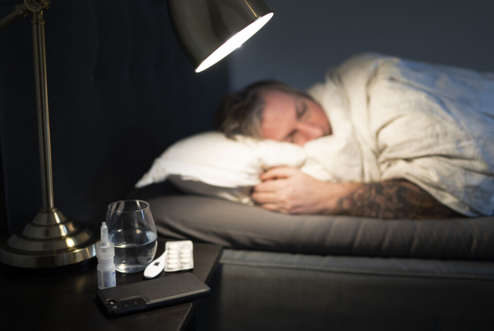 Norway has had the highest sickness absence rates in the Nordic countries every year since 2006, measured by the proportion of employees who have been away from work for one week as a result of illness. Mann ligger i seng. Vannglass, termometer, piller og nesespray på nattbordet.