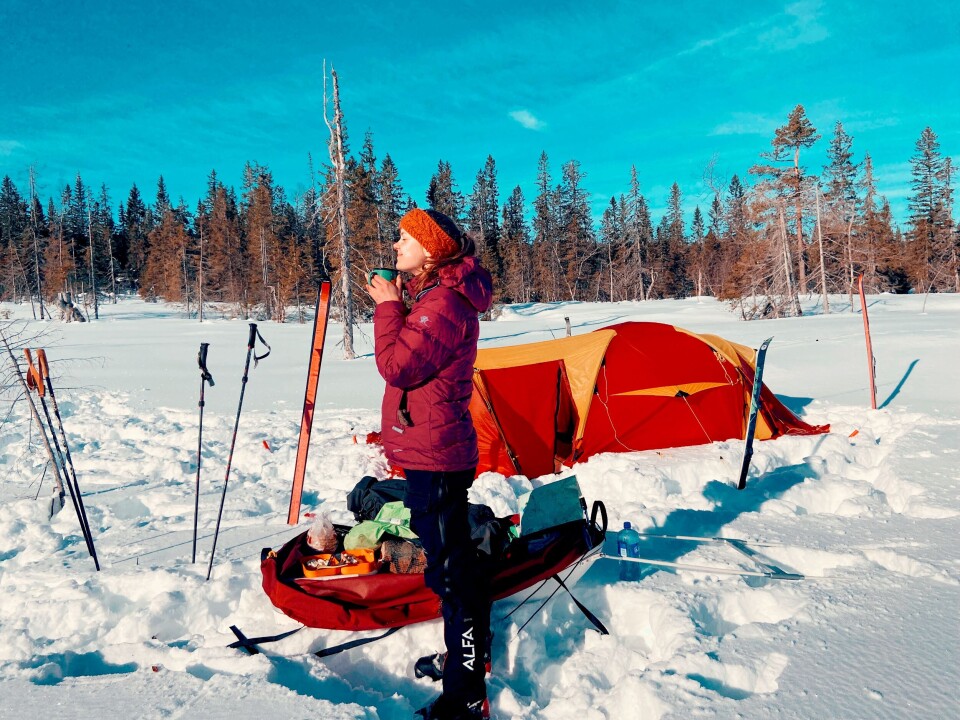 The researcher encourages disconnecting while you are on a trip and sharing photos only after returning home. This way, you can be more present and get more out of the experience. A woman grinning towards the sun on a trip in the snow.