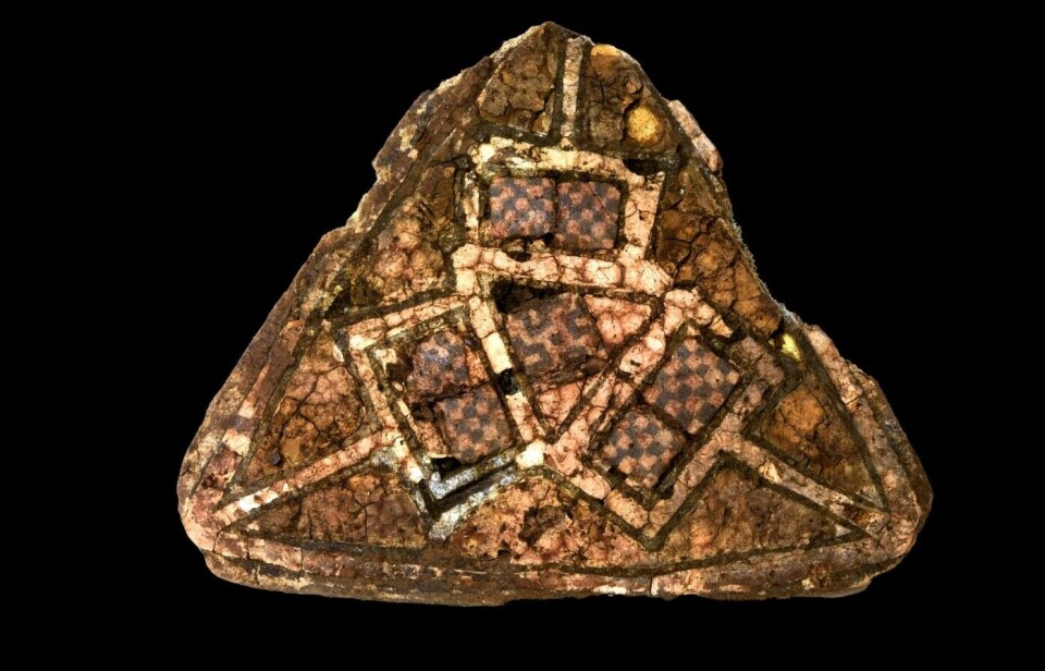 A triangular brooch with glass mosaic and gold enamel from Ireland or England was found in the grave within the rock crevice. This grave had been opened earlier. Remains of the grave goods were found outside and around the grave.