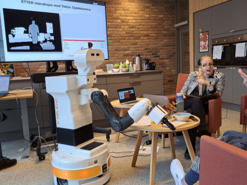 Researchers are conducting tests on interactions with a robot, with the person's face blurred for anonymity.