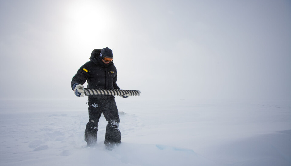 Our climate history is preserved in the ice. En forsker står ute i snøstorm og holder en iskjerne.