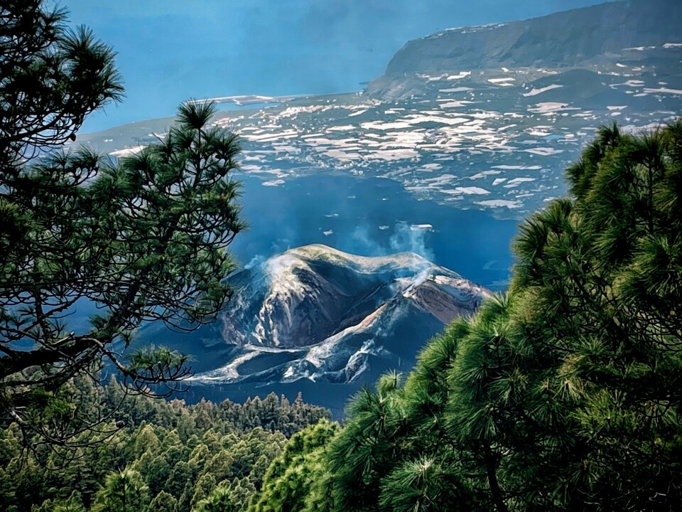 that you can almost look straight down into the new, smoking volcano, Cumbre Vieja. This is the volcano that erupted three years ago. Notice the black lava that has buried several thousand houses in the island’s largest city, Los Llanos de Aridane, which lies behind the volcano in this photo.