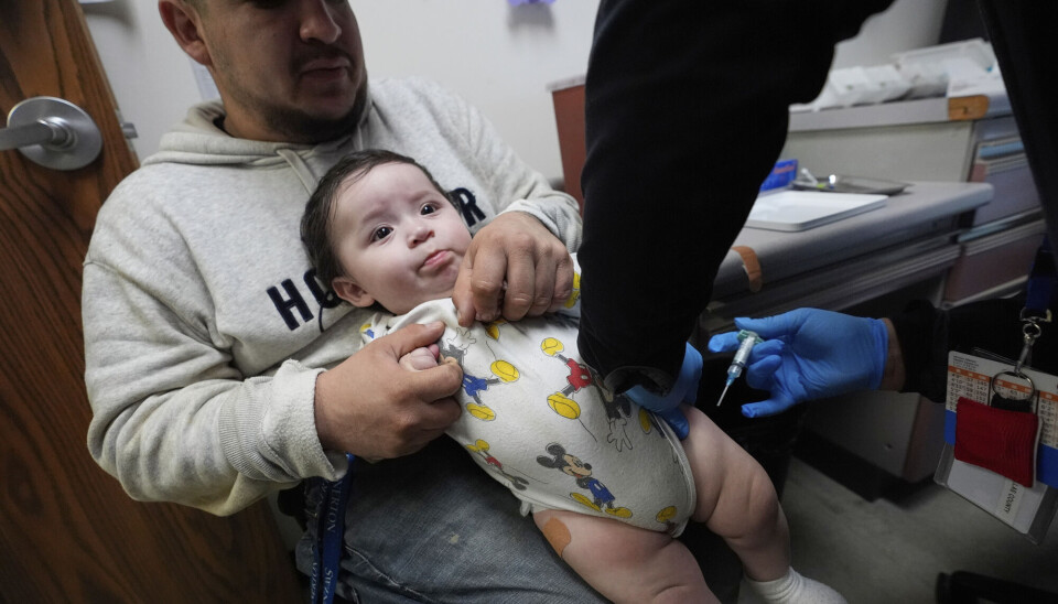 Little Adriel receives a vaccine at a clinic in Texas. His father Cesar Acevedo watches over him.