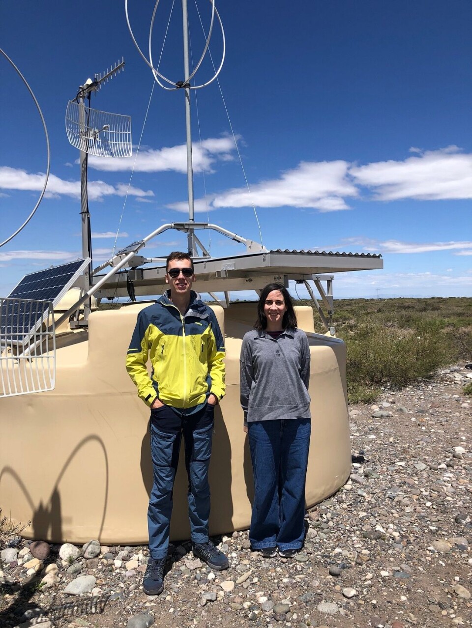 Domenik Ehlert and Foteini Oikonomou in front of one of the 1,600 surface detectors that are part of the Pierre Auger Ultra-high Energy Cosmic Ray Observatory in Malargüe, Argentina. To personer
