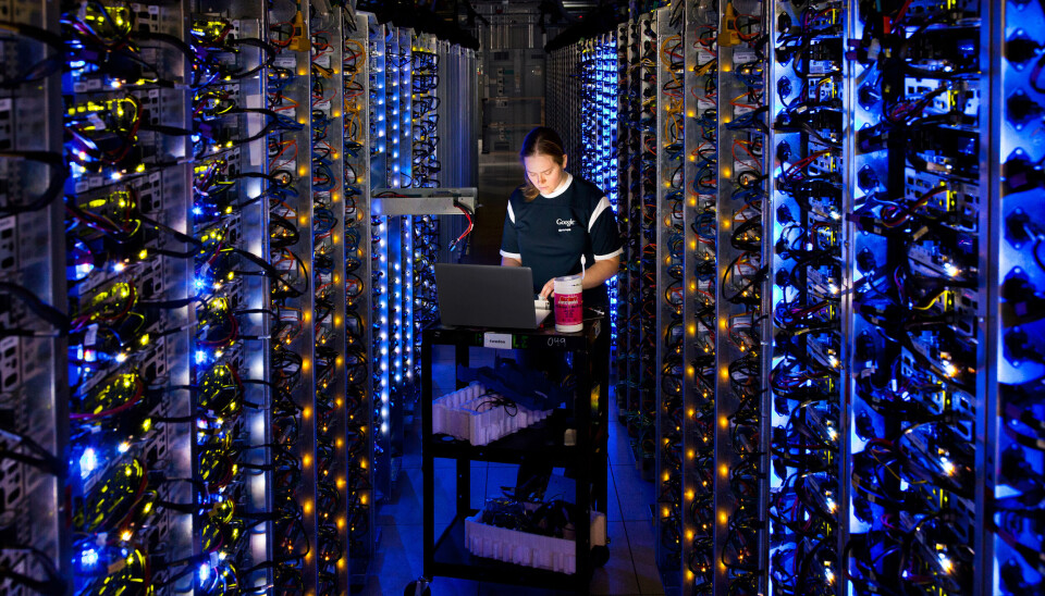 Data centres are packed with servers full of information ready to be sent around the world. En ingeniør står ved en laptop, omringet av dataservere som lyser.