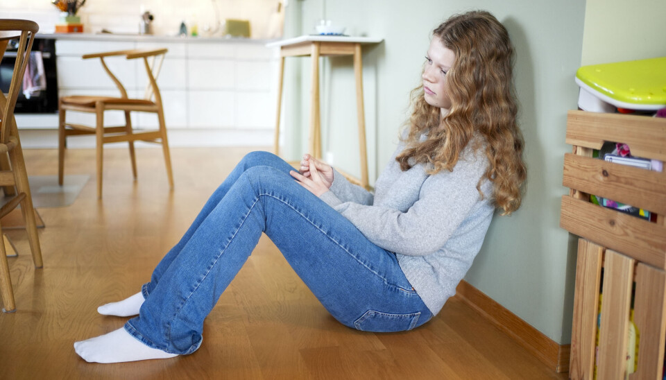 Historically, ADHD and autism have often been perceived as 'boy diagnoses,' leading to underdiagnosis in girls. Jente sitter på gulvet og tenker.