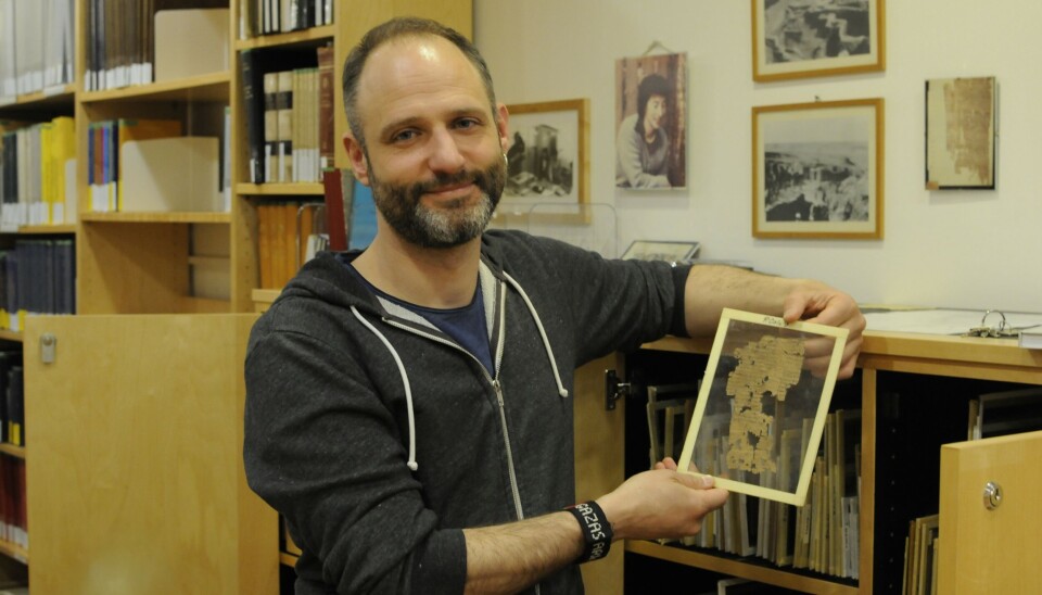 Federico Aurora holds up one of the text fragments in the collection, this one from The Statesman by Plato. Federico Aurora holder fram et papyrusark, innrammet i glass