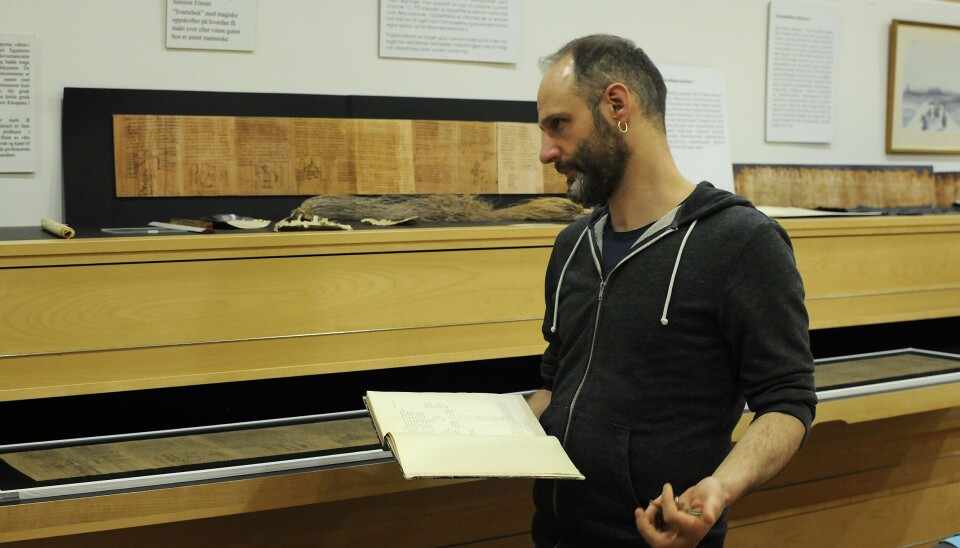 Federico Aurora with a book of published papyri. Federico Aurora står foran en skuff og holder en bok.