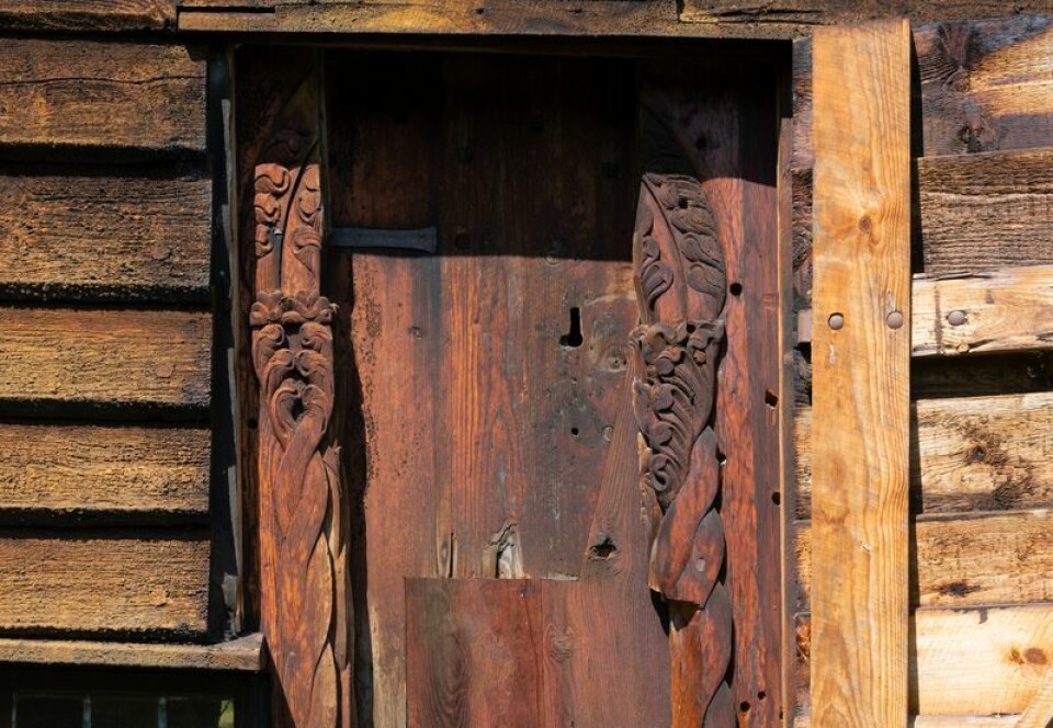 The portal at Rødven Stave Church is no longer in use and is usually hidden behind the cladding. Helhetsbilde av stavkirkeportal med utskjæringer. Utskjæringene forestiller bladverk og tvinnede bladstilker.
