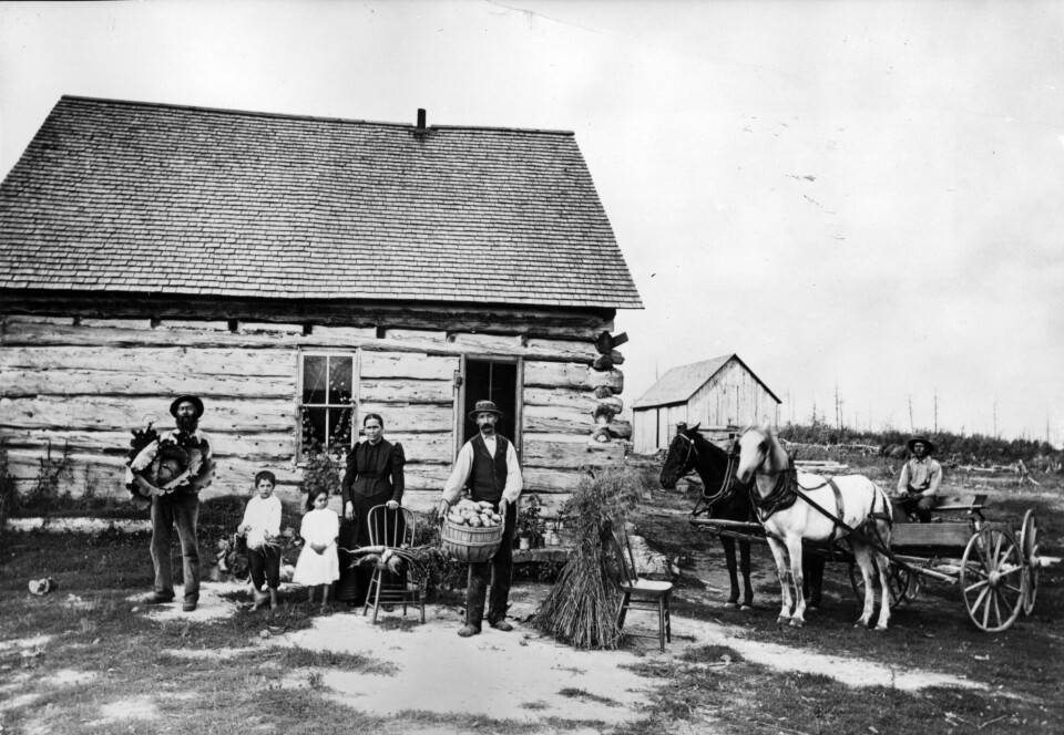 Immigrants were able to buy large plots of land at a low price after the Dakota people were forced out. This photo was taken in Minnesota a few years after the Dakota War. Nybyggere i USA foran hus. Historisk bilde.