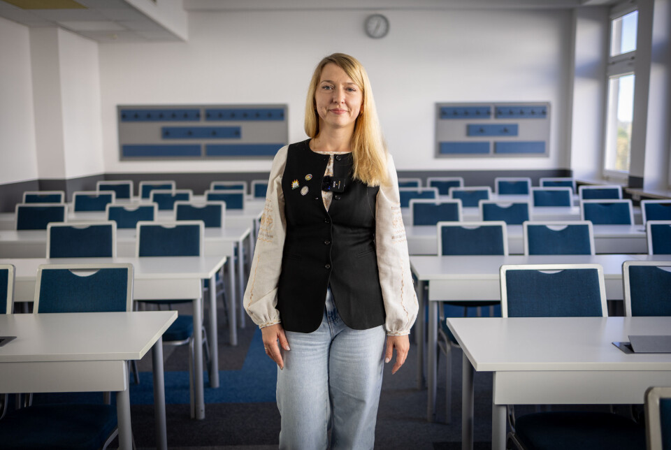 Kateryna Maksom from Chernihiv Polytechnic teaches under fire back home. Here she is photographed at Kozminski University in Warsaw. Researcher standing in the middle of an empty classroom.
