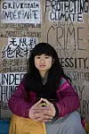 A young Chinese girl sits in front of cardboard signs.