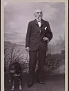 An old photograph of a man in a suit with a dog.