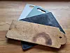Three plastic chopping boards and one wooden one stacked on a table.