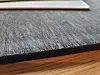 Close up of a black plastic cutting board with visible grooves and scratches.