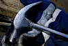 Close up of a hammer held in a gloved hand.