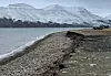 Coastal erosion as can be seen on Svalbard, with the sea and mountains in the background.